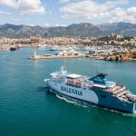 Traghetto passeggeri in navigazione verso le Isole Baleari, con un porto spagnolo in lontananza. (Immagine generata con IA)