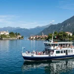 Traghetto turistico sul Lago Maggiore che si avvicina alle Isole Borromee con ville storiche e giardini. (Immagine generata con IA)