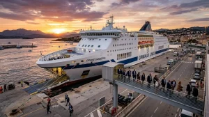 Una nave di Grimaldi Lines ormeggiata nel porto di Olbia, con persone che transitano su una passerella, a simboleggiare un evento a bordo. (Immagine generata con IA)